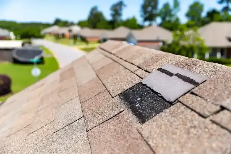 Roof with a torn shingle after wind damage